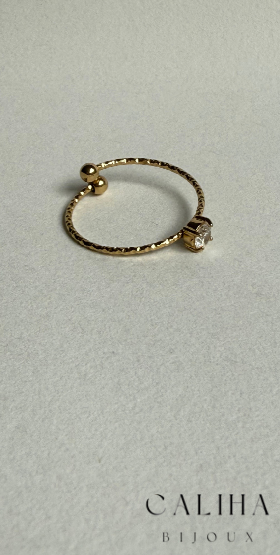 Vue rapprochée de la bague dorée avec anneau fin et une pierre scintillante discrète, mettant en avant son design épuré et raffiné – Bijou intemporel exposé sur fond clair