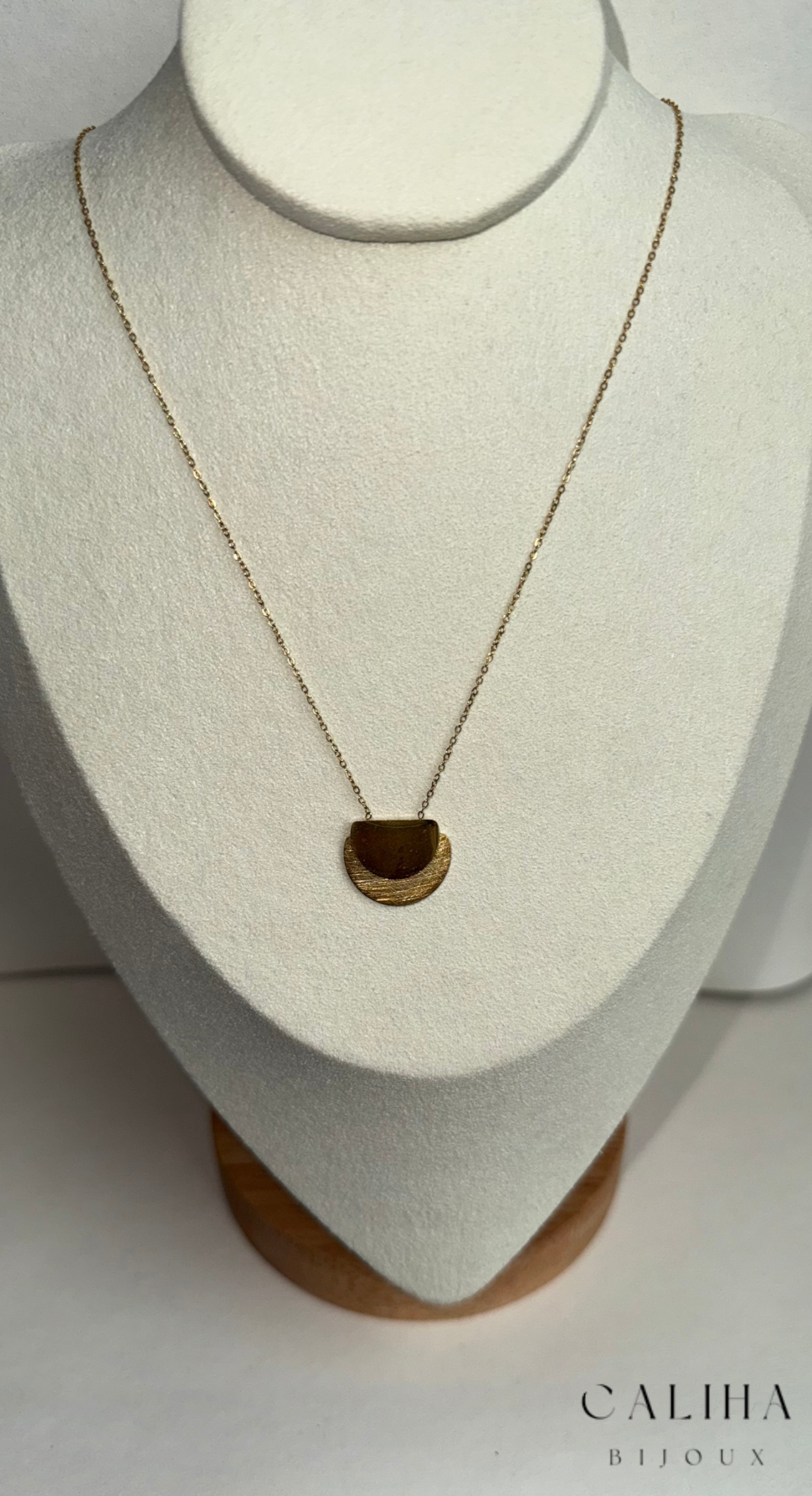 Collier doré avec chaîne fine et pendentif texturé en demi-cercle, présenté sur bustier blanc avec la marque CALIHA BIJOUX – Bijou élégant et moderne 